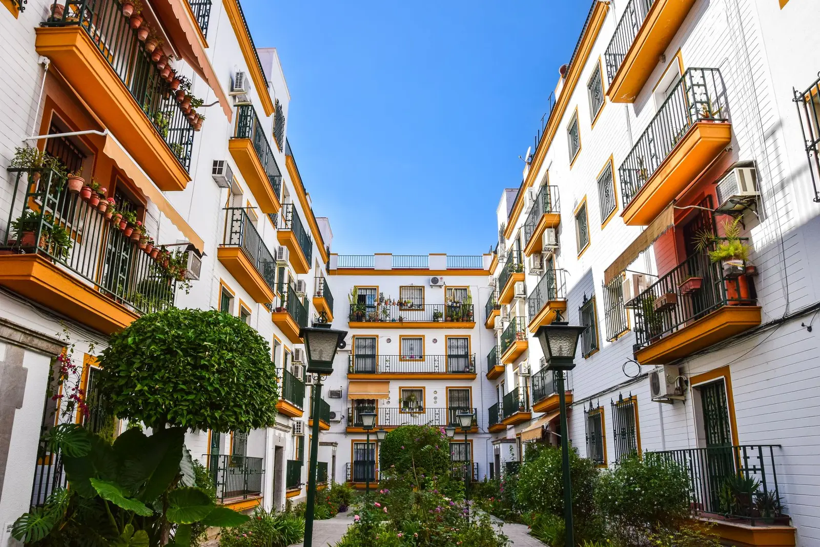 Patio interior de un bloque de viviendas en Sevilla con balcones y fachadas encaladas